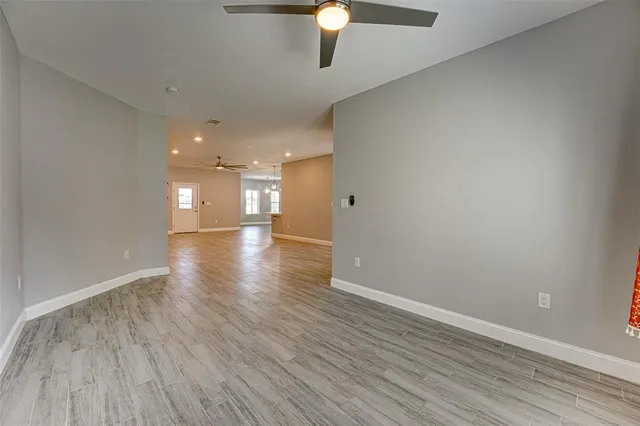 a view of an empty room with window and wooden floor