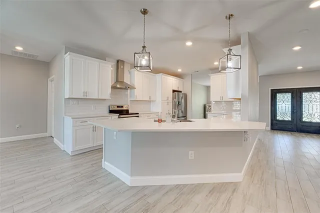 a large kitchen with stainless steel appliances kitchen island a large counter space a sink and a chandelier