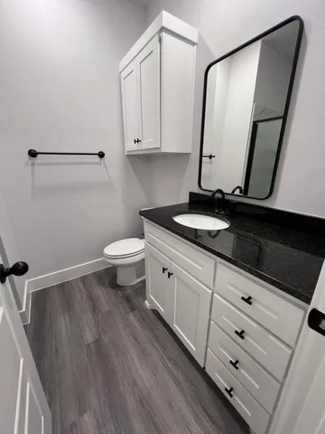 a bathroom with a granite countertop sink toilet and mirror