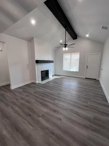 an empty room with wooden floor fireplace and windows