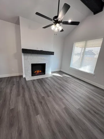 a view of an empty room with wooden floor fireplace and a window
