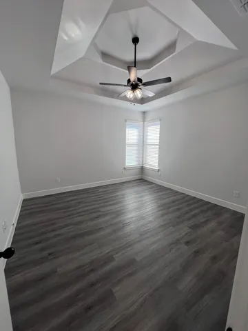a view of an empty room with wooden floor a ceiling fan and staircase