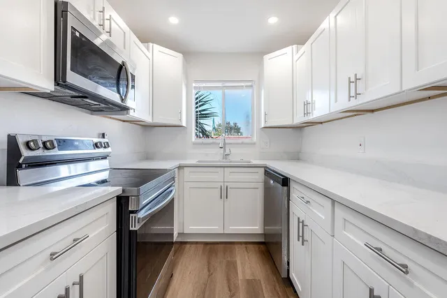 a kitchen with stainless steel appliances granite countertop a sink dishwasher a stove and a microwave oven with cabinets