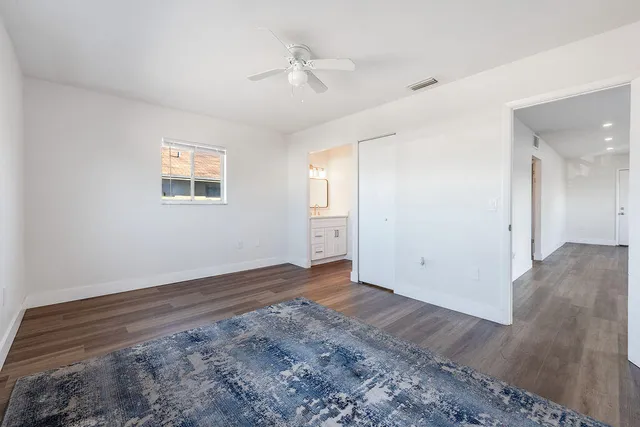 a view of an empty room with wooden floor and a ceiling fan