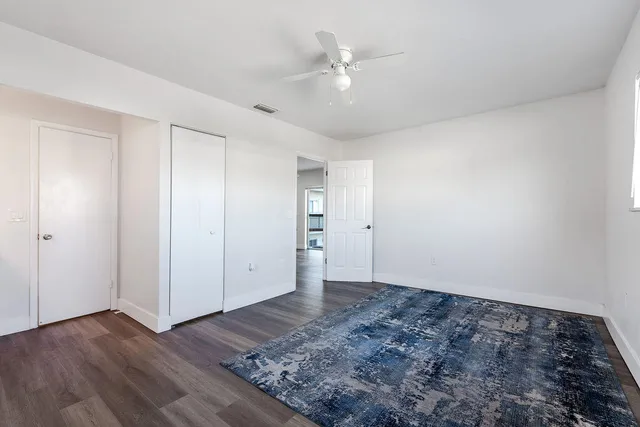 an empty room with wooden floor and ceiling fan