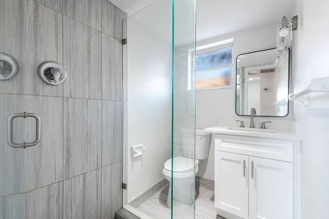 a bathroom with a granite countertop sink a toilet and a mirror