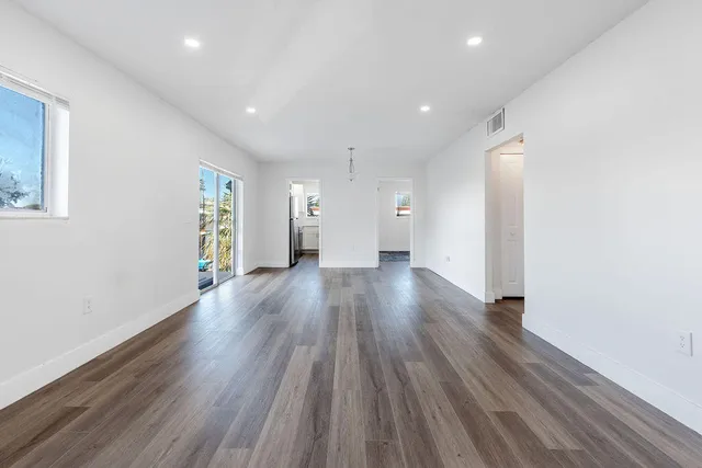 a view of a big room with wooden floor and windows