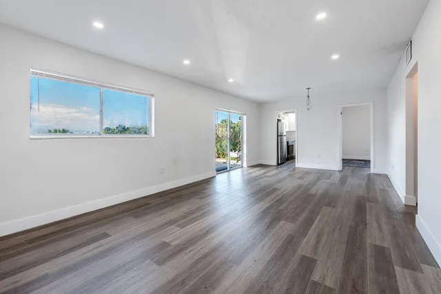 a view of an empty room with wooden floor and a window
