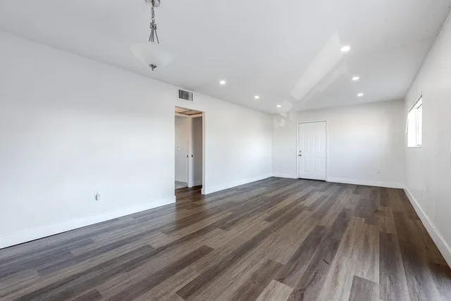 an empty room with wooden floor and windows