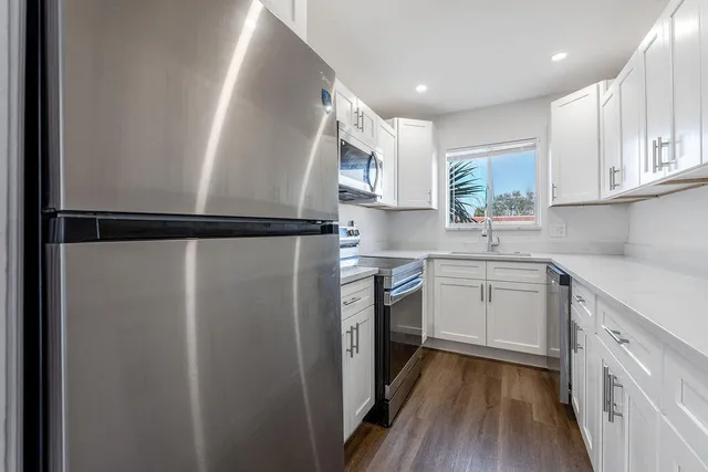 a kitchen with a sink a refrigerator a window and cabinets