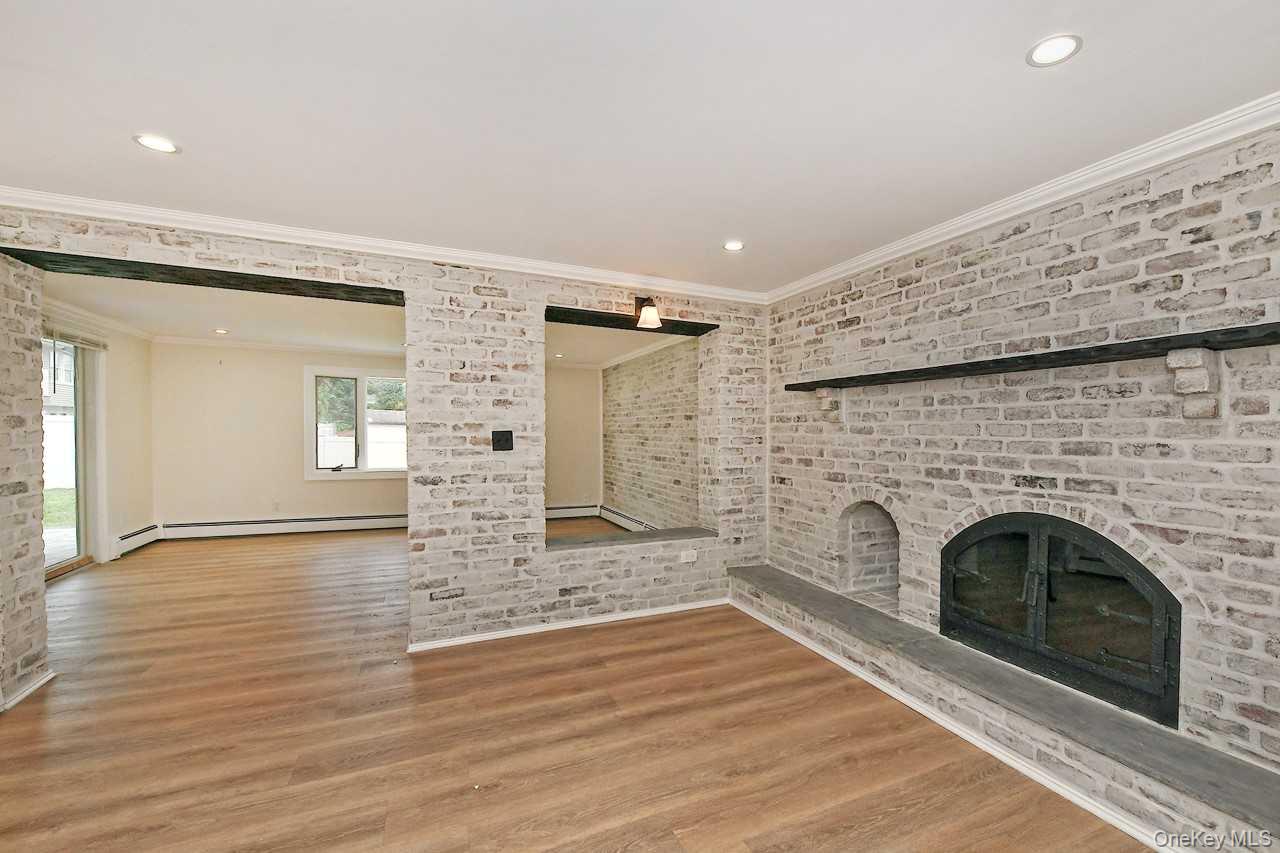 107 Beverly Road Massapequa, NY 11758 - Photo 26 of 41 a view of empty room with wooden floor and fireplace