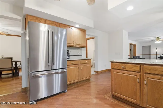 a kitchen with stainless steel appliances granite countertop a refrigerator a stove a sink dishwasher and a refrigerator with wooden floor