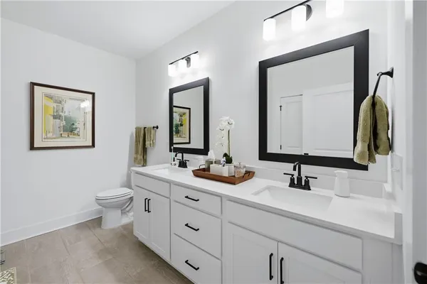 a bathroom with double vanity sinks a toilet and a mirror