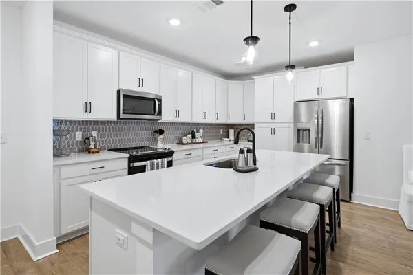 a kitchen that has a lot of white cabinets and stainless steel appliances