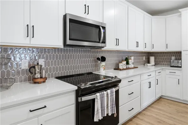 a kitchen with granite countertop white cabinets and black appliances
