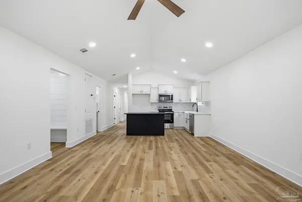 a large kitchen with kitchen island a sink dishwasher a stove and a refrigerator with wooden floor