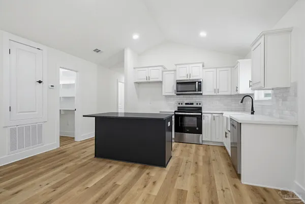 a kitchen with granite countertop a refrigerator and a stove top oven
