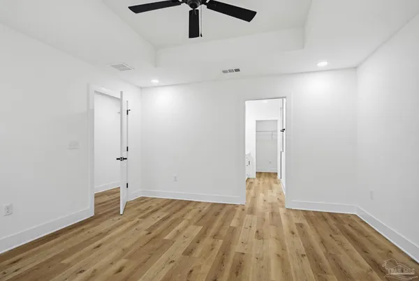 an empty room with wooden floor and ceiling fan