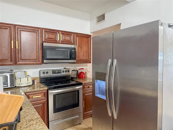 a kitchen with granite countertop a refrigerator stove and microwave