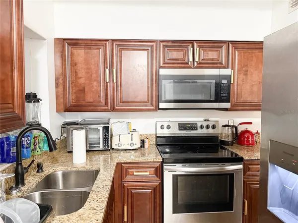 a kitchen with granite countertop a stove sink and microwave