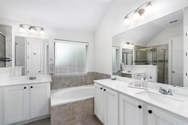a bathroom with a tub double vanity sink and mirror