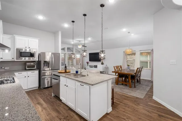 a kitchen with a stove a sink a kitchen island with chairs and wooden floor