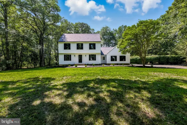 a view of a house with a big yard and large trees