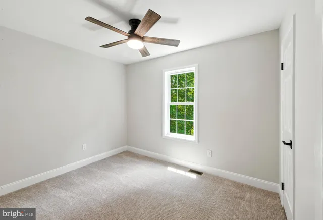 an empty room with a window and a fan