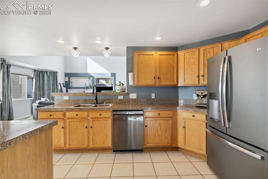 8518 Bohleen Road Peyton, CO 80831 - Photo 6 of 44 a kitchen with stainless steel appliances granite countertop a sink a stove a refrigerator and island with wooden cabinets
