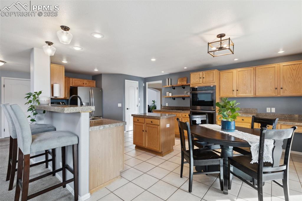 8518 Bohleen Road Peyton, CO 80831 - Photo 8 of 44 a kitchen with kitchen island a dining table chairs and white cabinets
