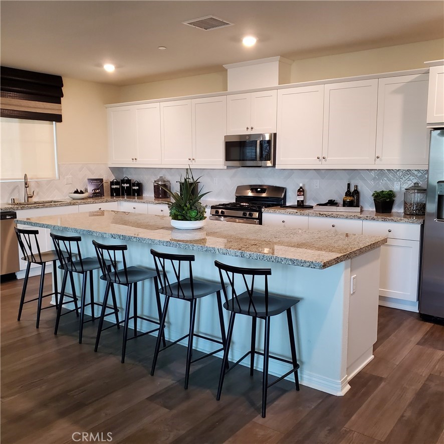 1701 Old Wagon Drive Hemet, CA 92545 - Photo 2 of 15 a kitchen with stainless steel appliances granite countertop a stove a sink a microwave a center island and chairs with wooden floor
