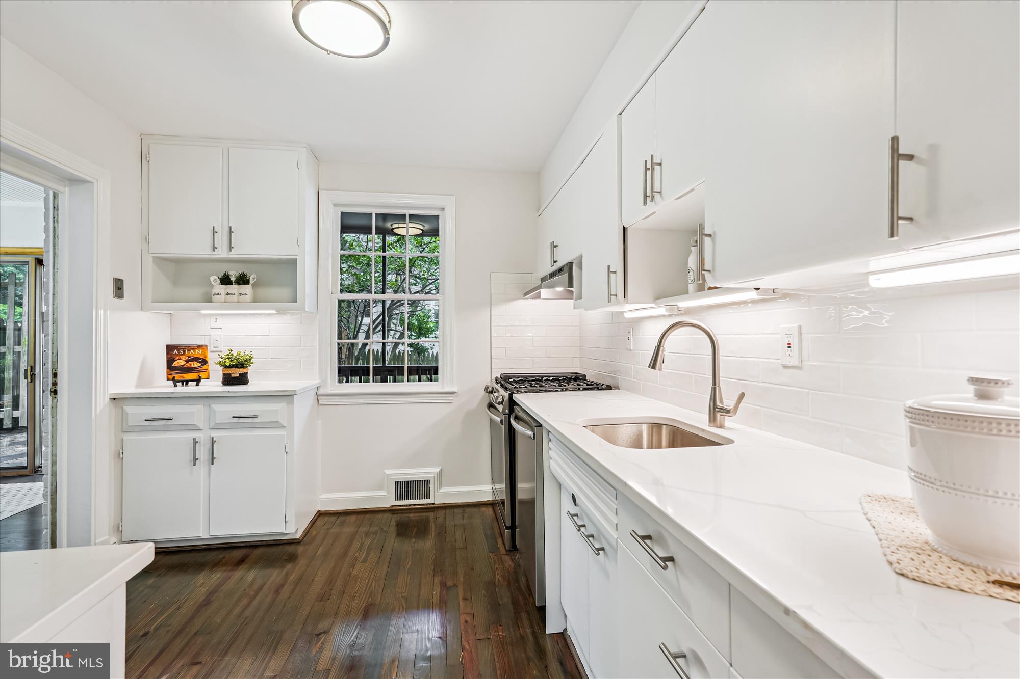 7206 Pinehurst Parkway Chevy Chase, MD 20815 - Photo 18 of 56 a kitchen with white cabinets a sink dishwasher and a stove with wooden floor