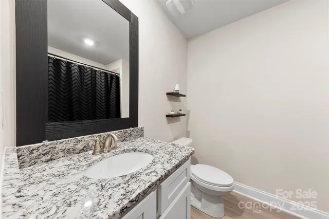 a bathroom with a granite countertop sink a toilet and a mirror