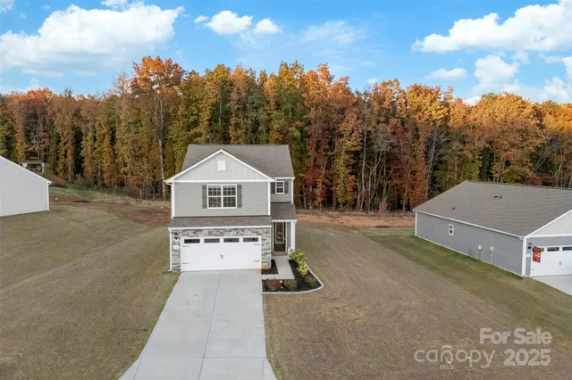 a view of a house with a yard and trees in the background
