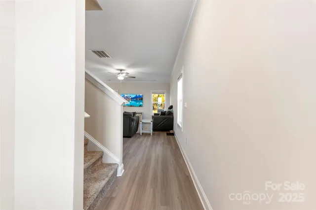 a view of a hallway with wooden floor and a bathroom