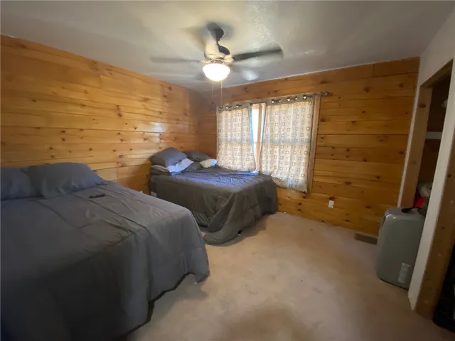 a spacious bedroom with two bed and a ceiling fan