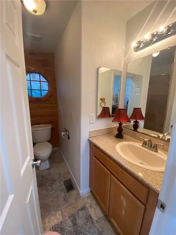 a bathroom with a granite countertop sink toilet and mirror