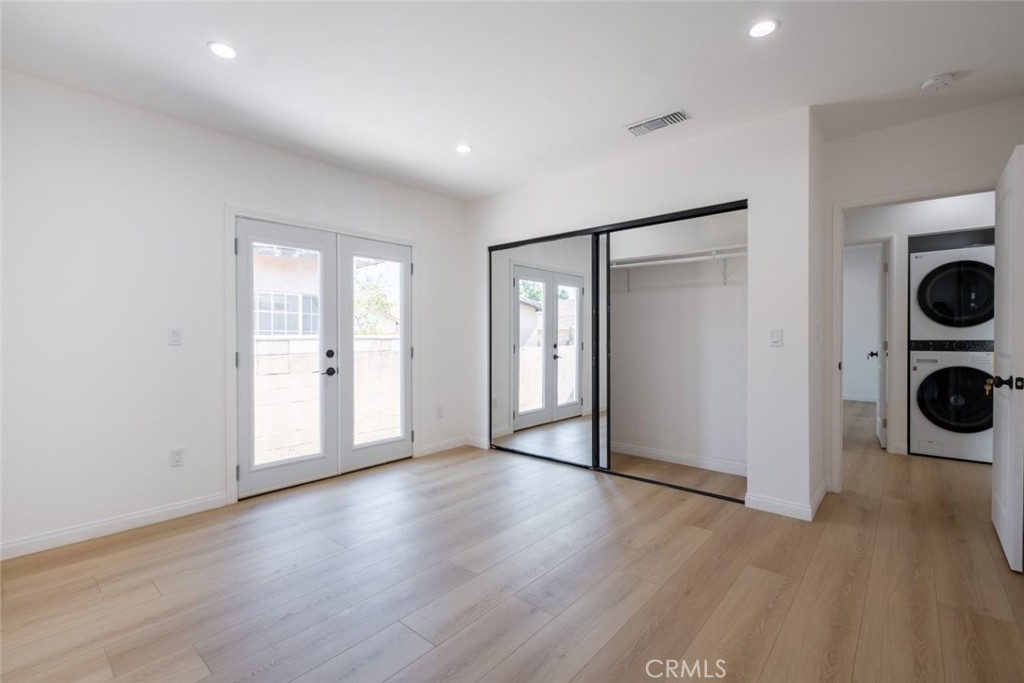 12974 Goleta Street Pacoima, CA 91331 - Photo 14 of 18 an empty room with wooden floor and washing machine and dryer