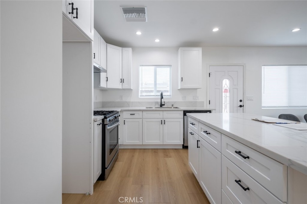 12974 Goleta Street Pacoima, CA 91331 - Photo 8 of 18 a kitchen with granite countertop white cabinets and stainless steel appliances