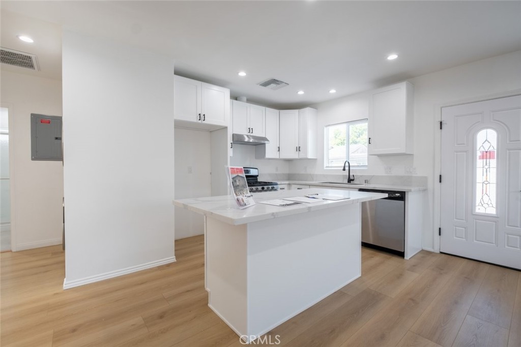 12974 Goleta Street Pacoima, CA 91331 - Photo 9 of 18 a kitchen with a sink a stove a refrigerator and white cabinets