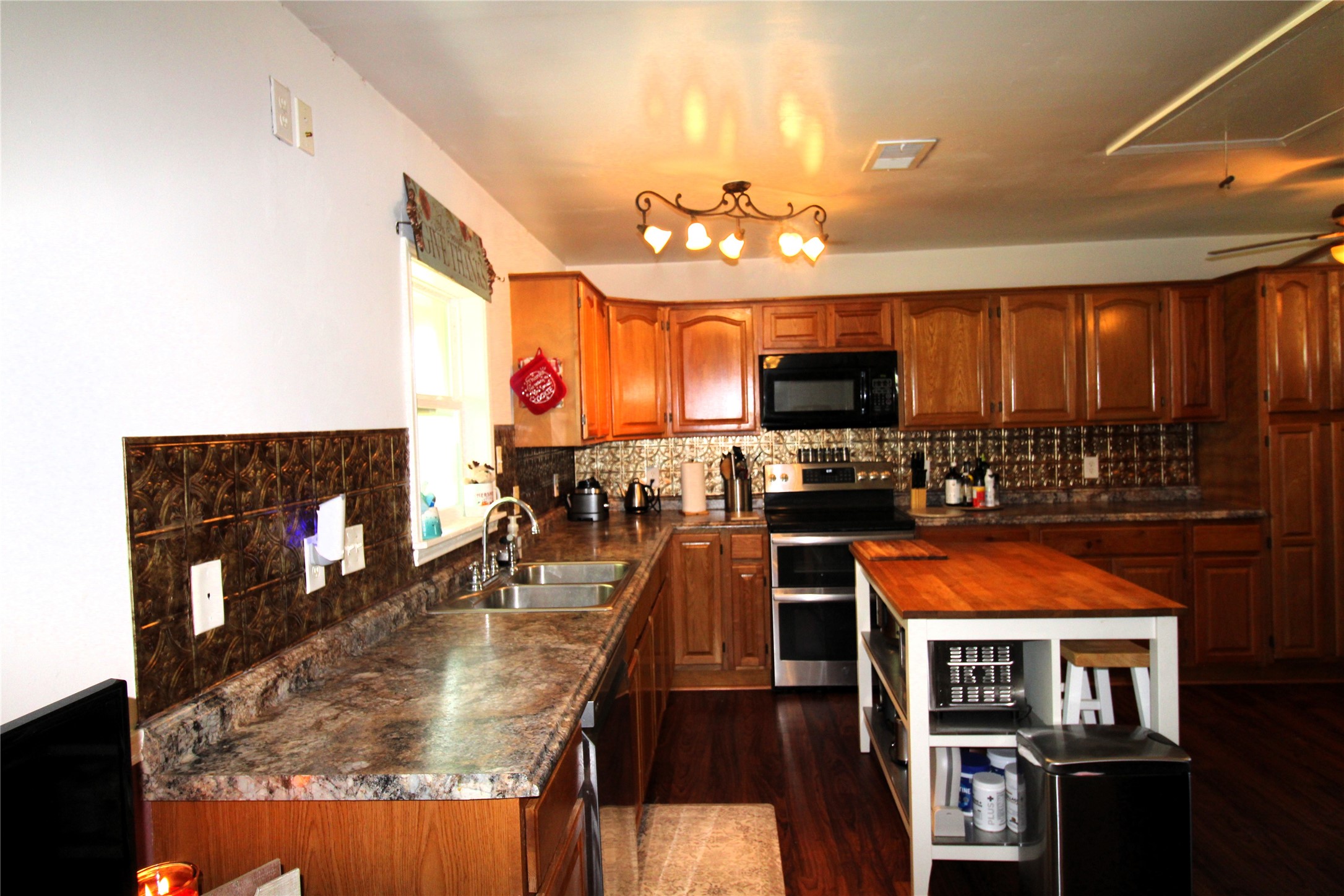 303 North 9th Street Beasley, TX 77417 - Photo 11 of 41 This spacious kitchen features warm wooden cabinetry, a central island with shelving, and an inviting light fixture.