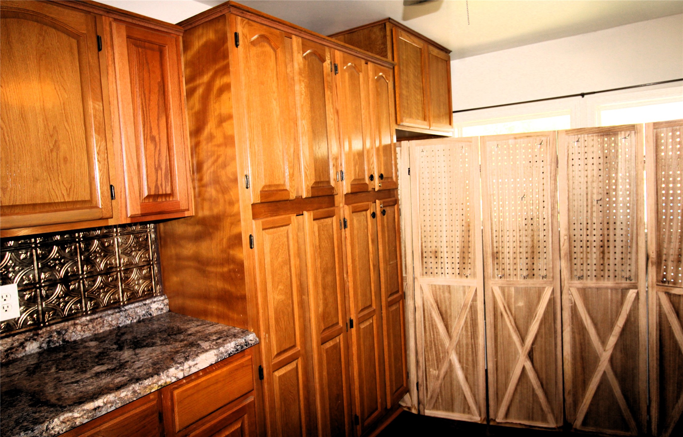 303 North 9th Street Beasley, TX 77417 - Photo 13 of 41 This photo features a kitchen with warm wooden cabinets offering ample storage and a folding wooden screen adds a rustic touch and separates the space.