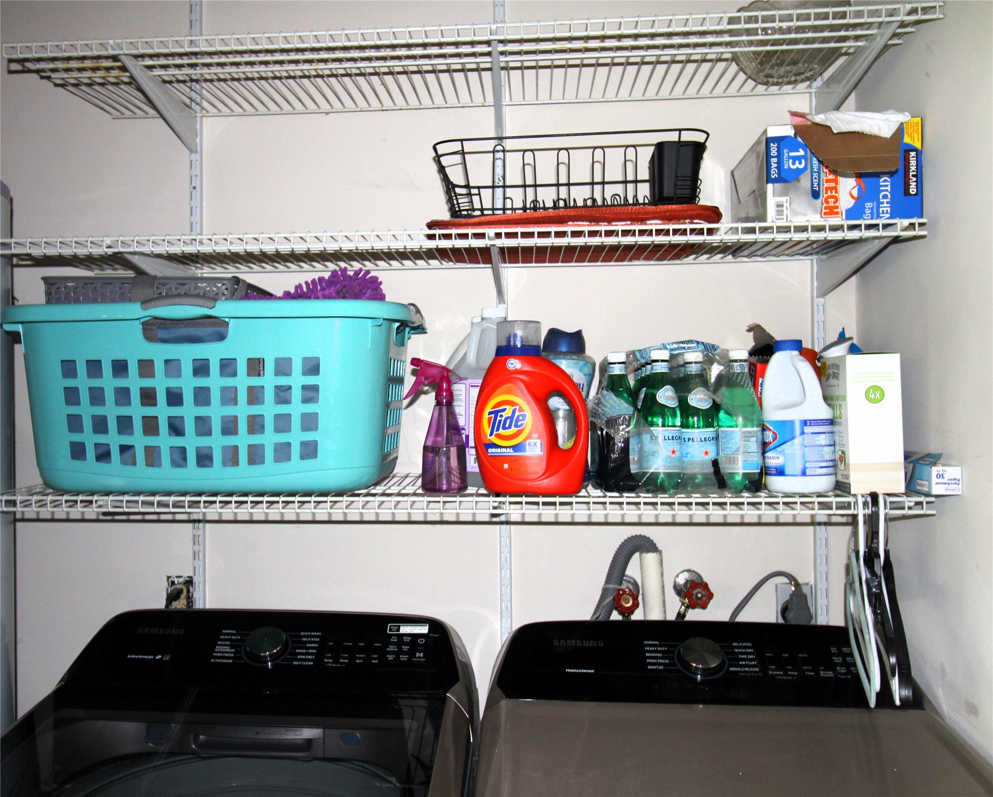303 North 9th Street Beasley, TX 77417 - Photo 16 of 41 This photo shows a laundry area equipped with modern appliances and organized shelving for storage. The shelves hold various cleaning supplies, a laundry basket, and other household items.