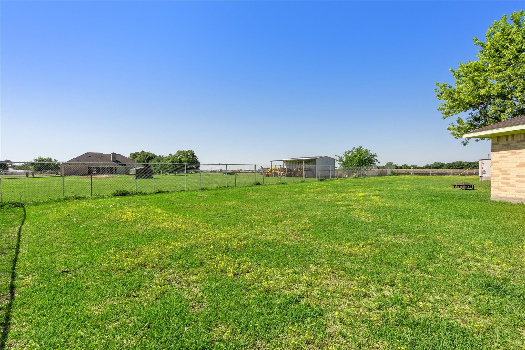 303 North 9th Street Beasley, TX 77417 - Photo 26 of 41 Huge fenced backyard with grass and clear blue skies, offering ample room for outdoor activities and relaxation.