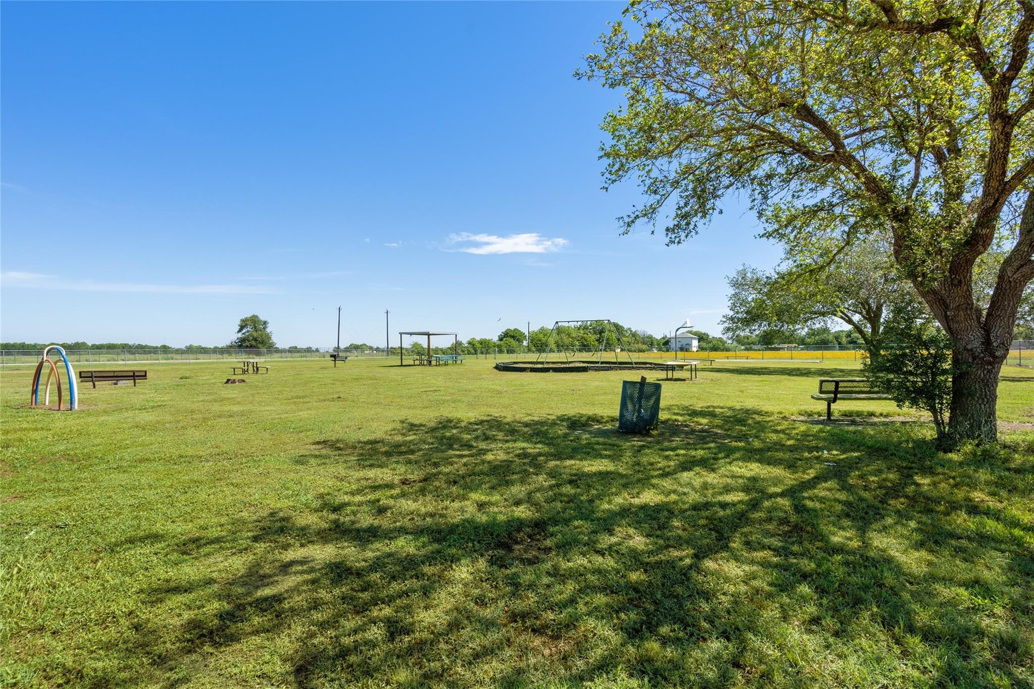 303 North 9th Street Beasley, TX 77417 - Photo 27 of 41 A spacious, open park area with green grass, benches, and a playground set under a clear blue sky. Ideal for outdoor activities and relaxation.
