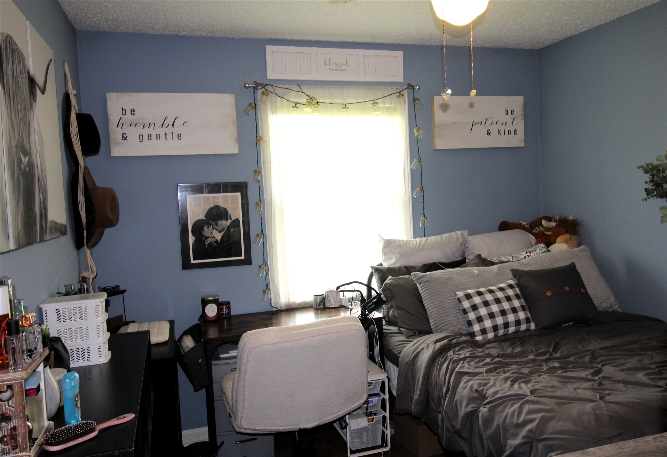 303 North 9th Street Beasley, TX 77417 - Photo 32 of 41 Cozy bedroom with blue walls, featuring a wooden dresser and TV stand with a flat-screen TV. Decorative wall art and a guitar add charm. The room has a modern rustic vibe with personalized touches, creating a welcoming atmosphere.
