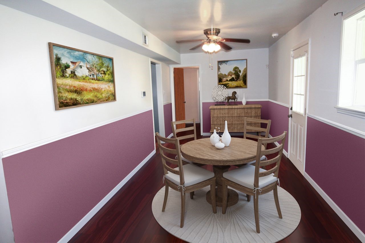 303 North 9th Street Beasley, TX 77417 - Photo 5 of 41 This cozy dining area features a round wooden table with four chairs, set on a circular rug. The room has a stylish two-tone wall design with white and mauve, complemented by artwork. A ceiling fan and ample natural light from a nearby window complete the space.