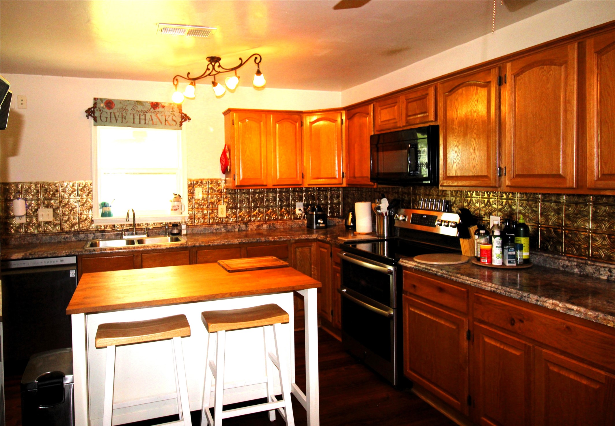 303 North 9th Street Beasley, TX 77417 - Photo 8 of 41 This kitchen features stainless steel double oven, and a decorative backsplash. It includes a central island with seating, overhead lighting, and ample counter space. Ideal for both cooking and entertaining.