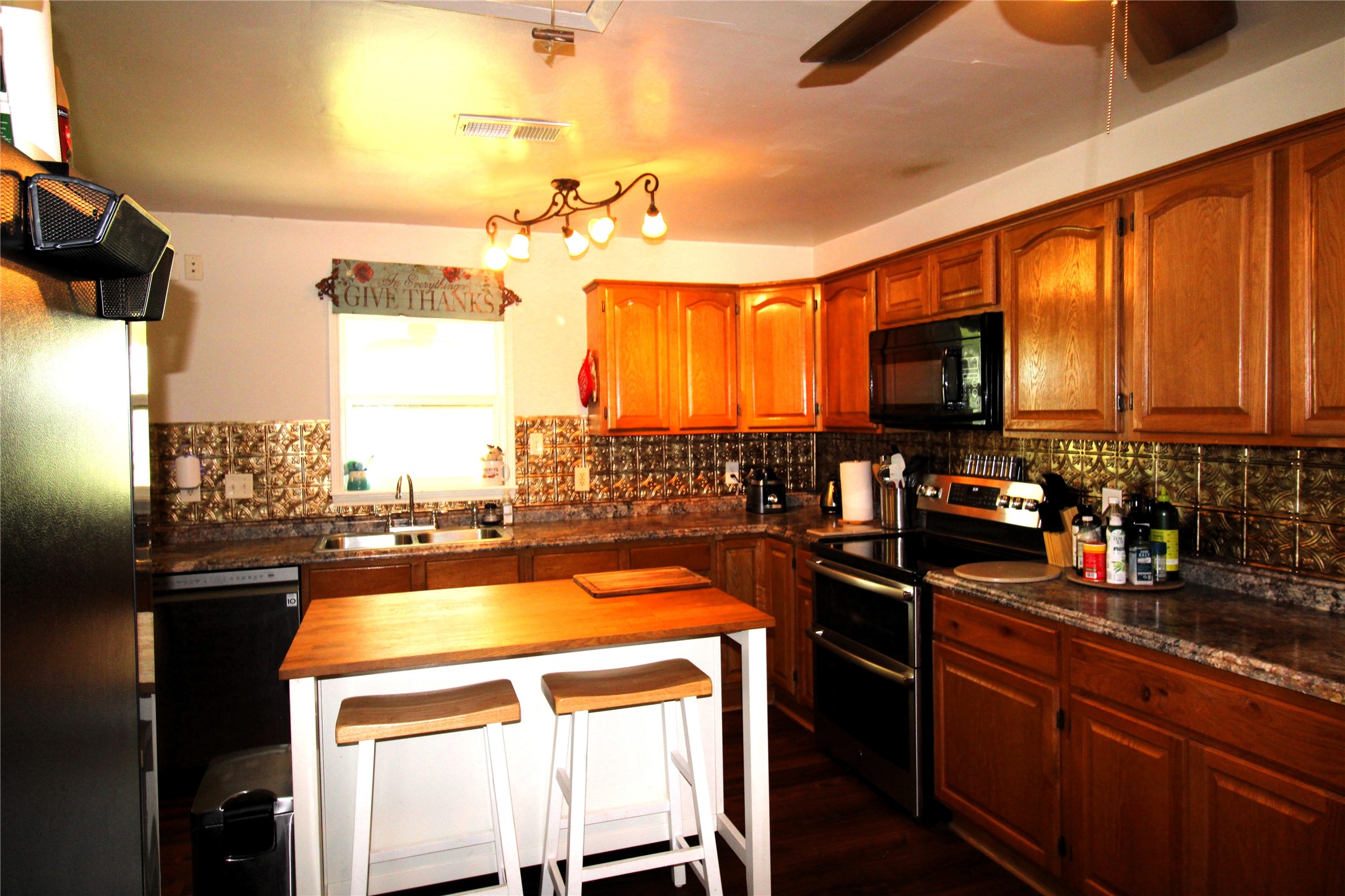 303 North 9th Street Beasley, TX 77417 - Photo 10 of 41 This kitchen features kitchen window, a central island with seating, and ample counter space, creating a cozy and functional cooking area.