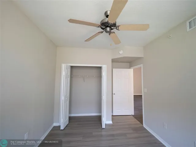 a view of a room with wooden floor and ceiling fan